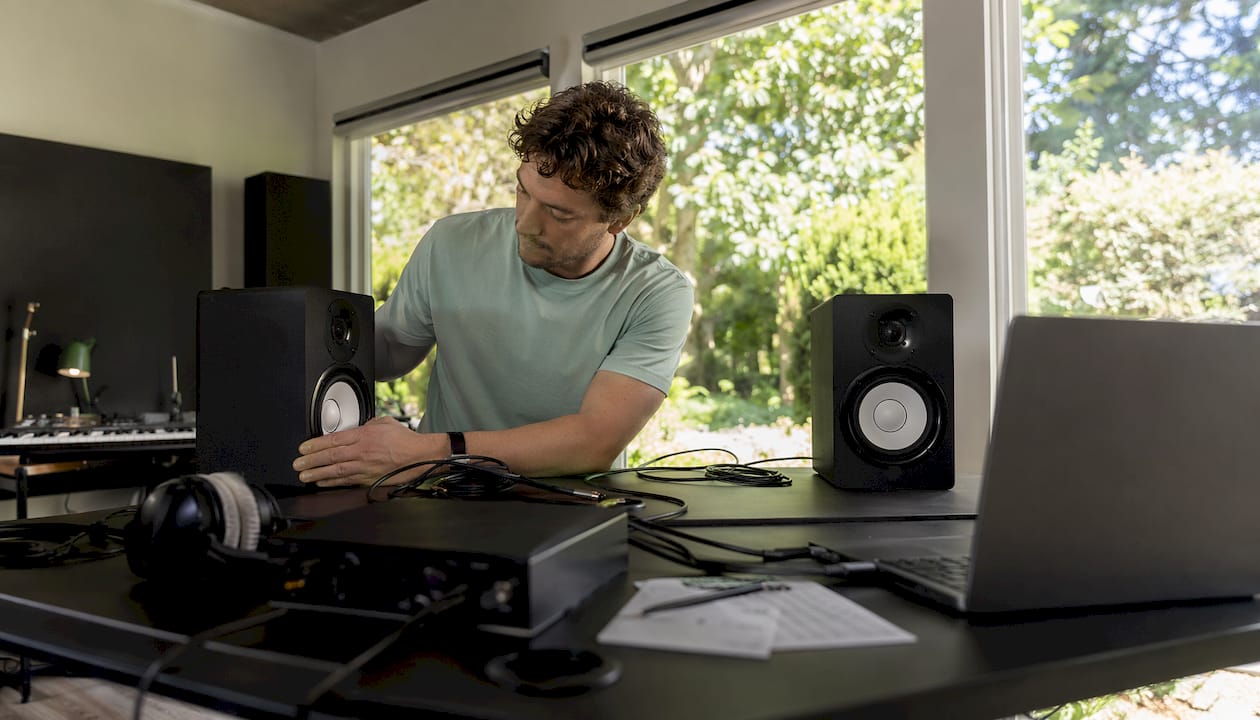 How to Set Up Studio Monitors: A Complete Installation Guide 3 Een muzikant richt zijn thuisstudio in en zet de studiomonitoren op de juiste plek.